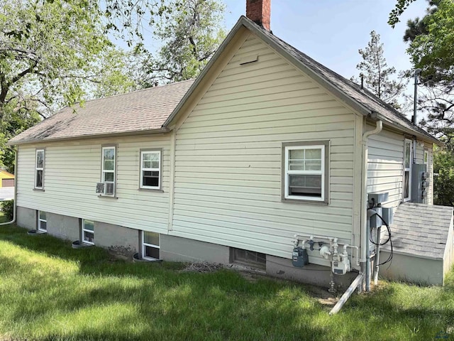 831 Dilger Ave, Rapid City, SD 57701 - view of side of property featuring a chimney, a lawn, cooling unit, and a shingled roof