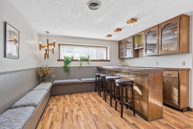 3513 Chapel Valley Rd, Rapid City, SD 57702 - indoor bar with light wood-style floors, a textured ceiling, and a chandelier