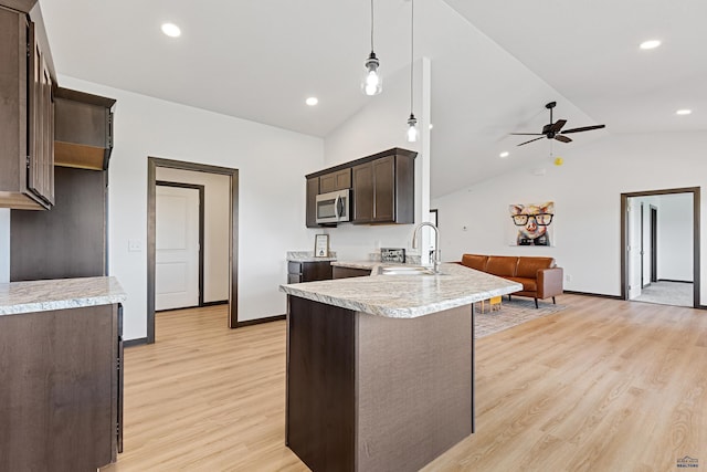 3053 Hoefer Ave, Rapid City, SD 57701 - kitchen featuring stainless steel microwave, dark brown cabinetry, lofted ceiling, a peninsula, and light countertops