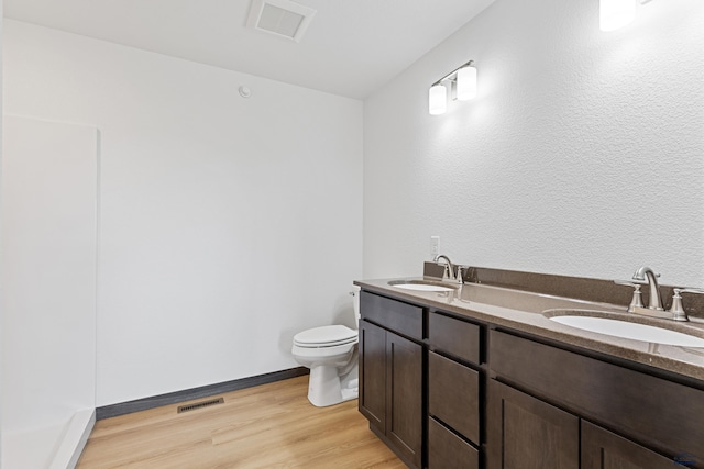 3053 Hoefer Ave, Rapid City, SD 57701 - bathroom featuring toilet, wood finished floors, double vanity, and baseboards
