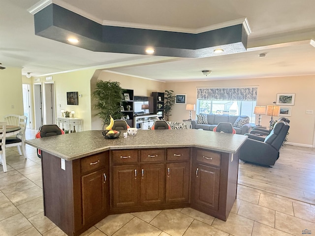 1222 Foothill Dr, Spearfish, SD 57783 - kitchen featuring open floor plan, crown molding, light tile patterned floors, a kitchen island, and dark brown cabinetry