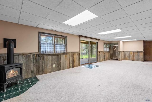 13741 Chipmunk Pl, Rapid City, SD 57702 - unfurnished living room featuring a wainscoted wall, wooden walls, a wood stove, and a drop ceiling