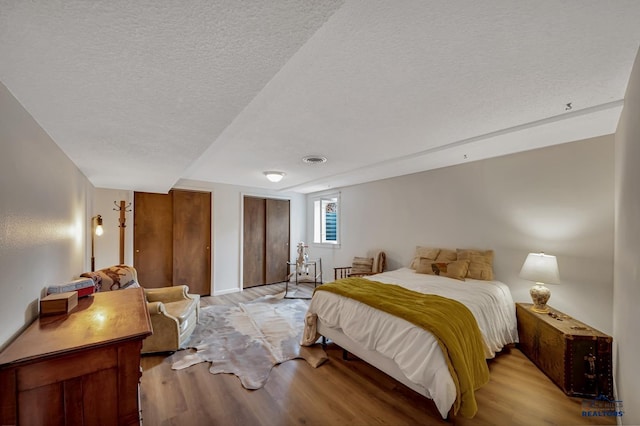 3112 Flint Dr, Rapid City, SD 57702 - bedroom with light wood-type flooring, a textured ceiling, and multiple closets