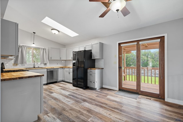 1705 Copperdale Dr, Rapid City, SD 57703 - kitchen with stainless steel dishwasher, black refrigerator with ice dispenser, wood counters, vaulted ceiling, and tasteful backsplash