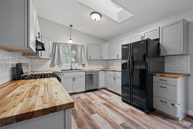 1705 Copperdale Dr, Rapid City, SD 57703 - kitchen with butcher block countertops, stainless steel dishwasher, black fridge, a skylight, and a sink
