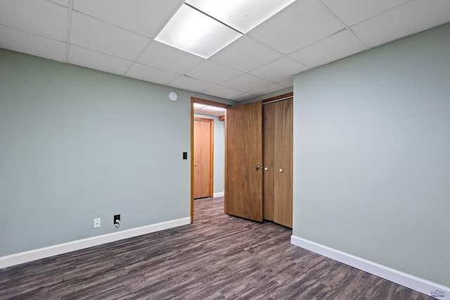 1705 Copperdale Dr, Rapid City, SD 57703 - unfurnished bedroom featuring dark wood-style flooring, baseboards, a drop ceiling, and a closet
