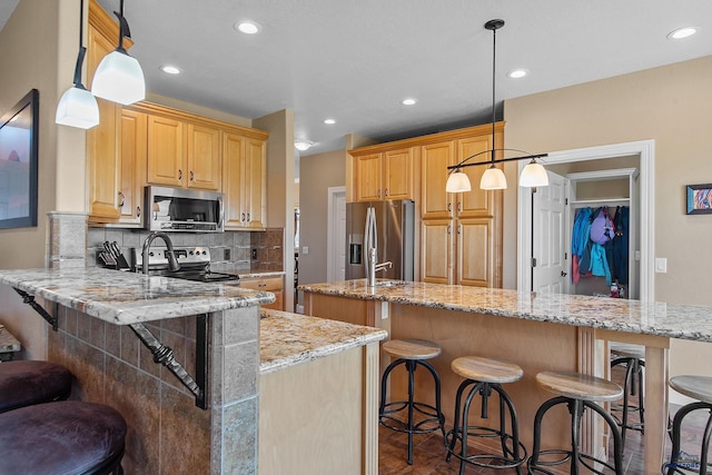 1120 S Regency Ct, Rapid City, SD 57702 - kitchen with appliances with stainless steel finishes, a peninsula, a kitchen bar, an island with sink, and recessed lighting