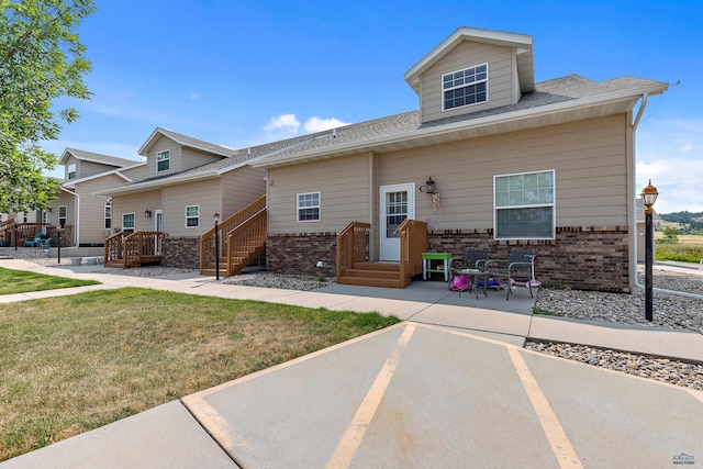 768 Earleen St Unit F, Rapid City, SD 57701 - bungalow featuring brick siding, a front lawn, roof with shingles, and a patio area