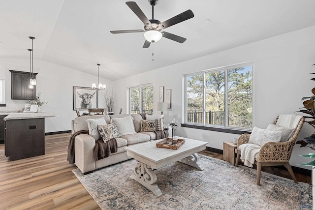 1246 Pinnacle Ct, Rapid City, SD 57701 - living area featuring light wood-style floors, vaulted ceiling, a ceiling fan, a chandelier, and baseboards