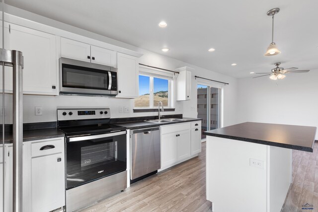 1740 Harmony Heights Ln, Rapid City, SD 57702 - kitchen featuring appliances with stainless steel finishes, dark countertops, a sink, ceiling fan, and white cabinetry