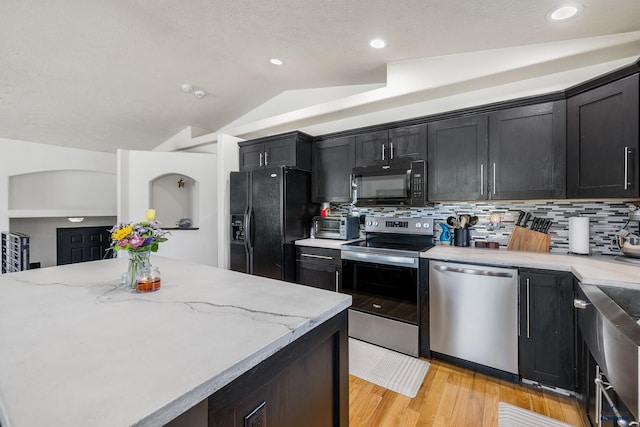 2909 Hoefer Ave, Rapid City, SD 57701 - kitchen featuring black appliances, dark cabinets, lofted ceiling, light wood finished floors, and tasteful backsplash