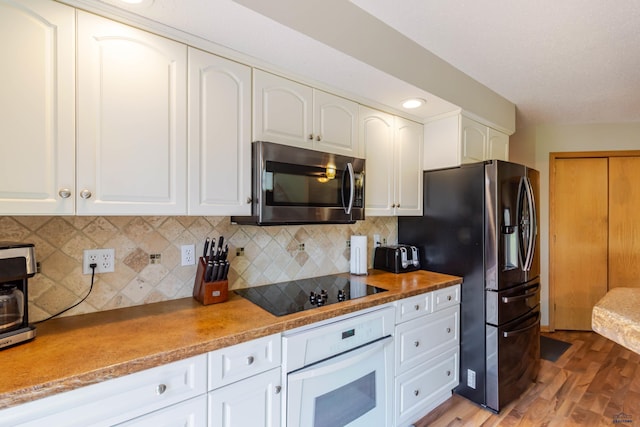 4941 Springtree Ct, Rapid City, SD 57702 - kitchen with stainless steel appliances, light wood-type flooring, white cabinetry, and decorative backsplash