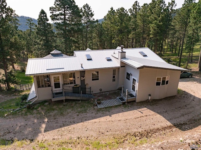 12525 Jax Ct, Rapid City, SD 57701 - rear view of property featuring a chimney, a metal roof, and a view of trees