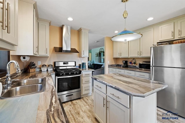 28085 Hargins Rd, Hot Springs, SD 57747 - kitchen featuring stainless steel appliances, wall chimney exhaust hood, a center island, light wood-style floors, and hanging light fixtures