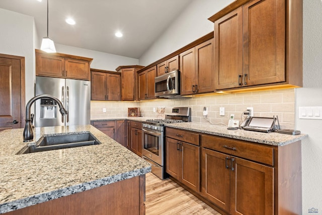 4519 Jolly Ln, Rapid City, SD 57701 - kitchen with stainless steel appliances, light wood finished floors, light stone counters, tasteful backsplash, and vaulted ceiling