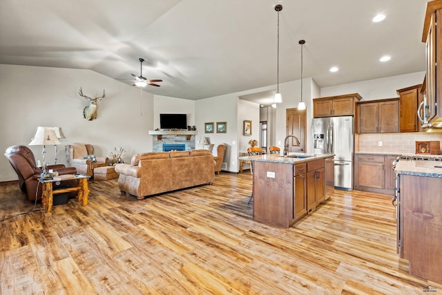 4519 Jolly Ln, Rapid City, SD 57701 - kitchen with stainless steel fridge with ice dispenser, open floor plan, light wood finished floors, ceiling fan, and light stone countertops