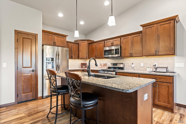 4519 Jolly Ln, Rapid City, SD 57701 - kitchen with stainless steel appliances, backsplash, light wood finished floors, a center island with sink, and lofted ceiling