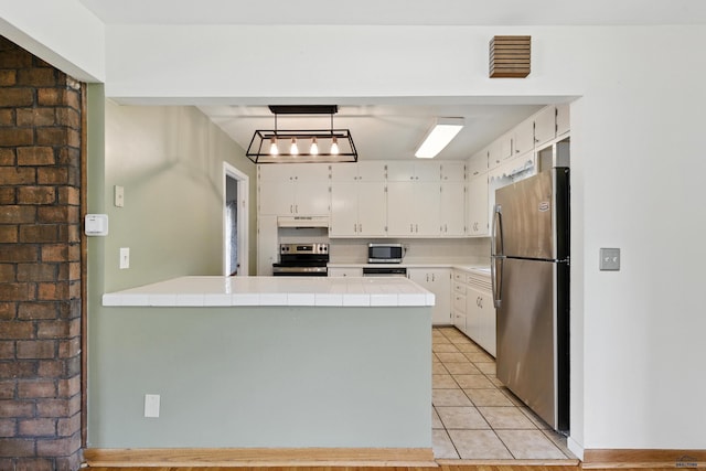 4340 Timothy, Rapid City, SD 57702 - kitchen featuring stainless steel appliances, tile countertops, a peninsula, under cabinet range hood, and white cabinets