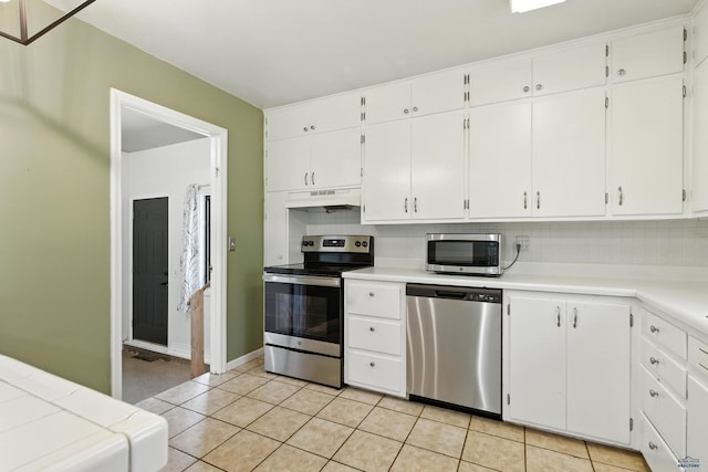 4340 Timothy, Rapid City, SD 57702 - kitchen with stainless steel appliances, tasteful backsplash, under cabinet range hood, white cabinetry, and light tile patterned floors