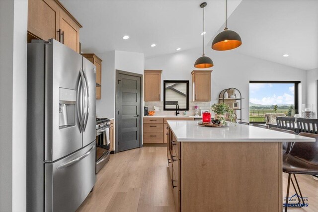 2147 Talisker Ave, Spearfish, SD 57783 - kitchen featuring stainless steel appliances, light wood-style floors, lofted ceiling, a breakfast bar area, and a center island