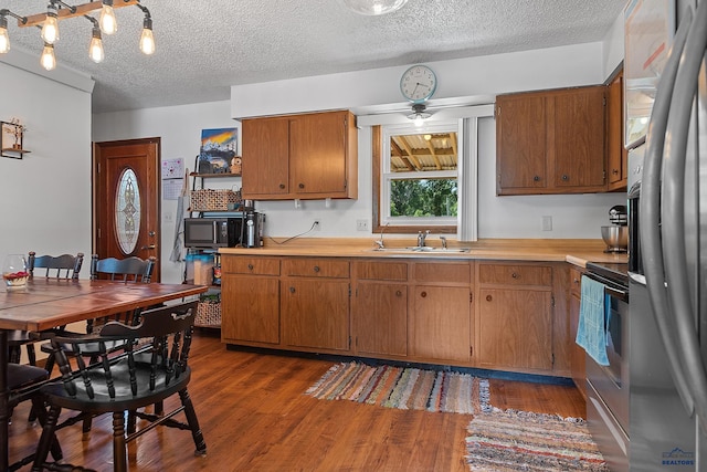 2613 Moose Dr, Sturgis, SD 57785 - kitchen featuring appliances with stainless steel finishes, light countertops, brown cabinets, wood finished floors, and ceiling fan