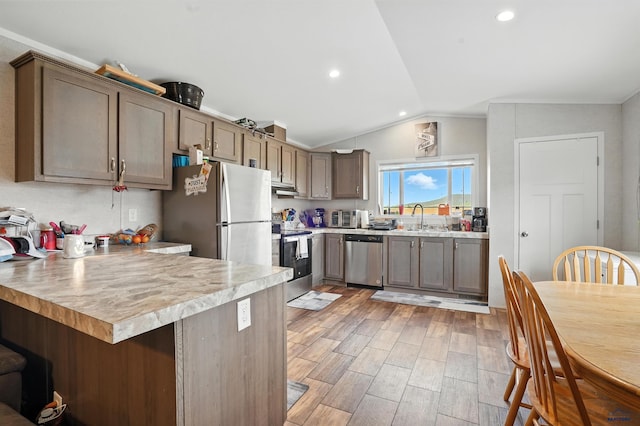 3053 Trailhead Loop, Sturgis, SD 57785 - kitchen featuring appliances with stainless steel finishes, a peninsula, light countertops, vaulted ceiling, and light wood finished floors