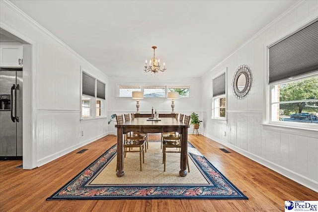 dining room featuring crown molding, wood finished floors, visible vents, and a notable chandelier