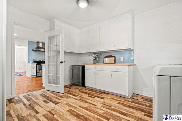 kitchen featuring wine cooler, electric range, light wood-style floors, wall chimney range hood, and backsplash