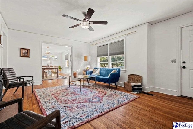 living room with ceiling fan with notable chandelier, baseboards, and wood finished floors