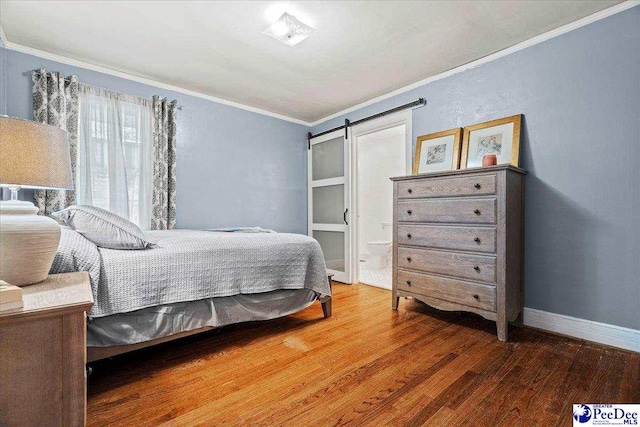 bedroom featuring baseboards, a barn door, ornamental molding, and wood finished floors