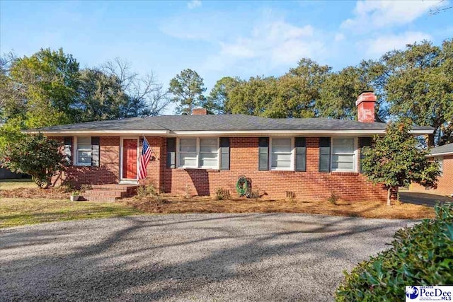 ranch-style house featuring brick siding and a chimney