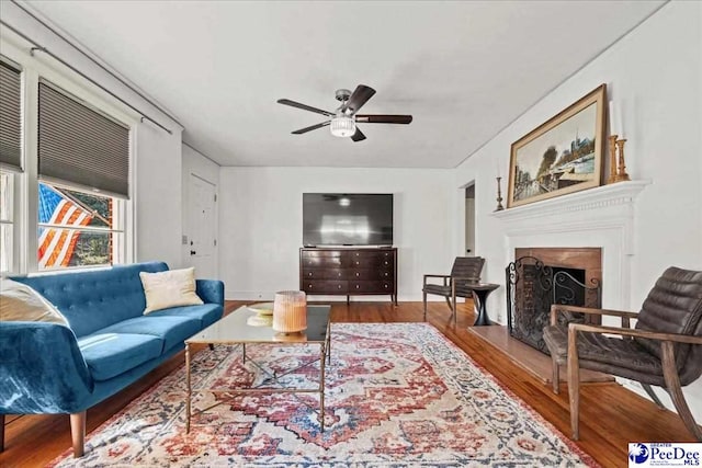 living area featuring a fireplace, wood finished floors, and a ceiling fan