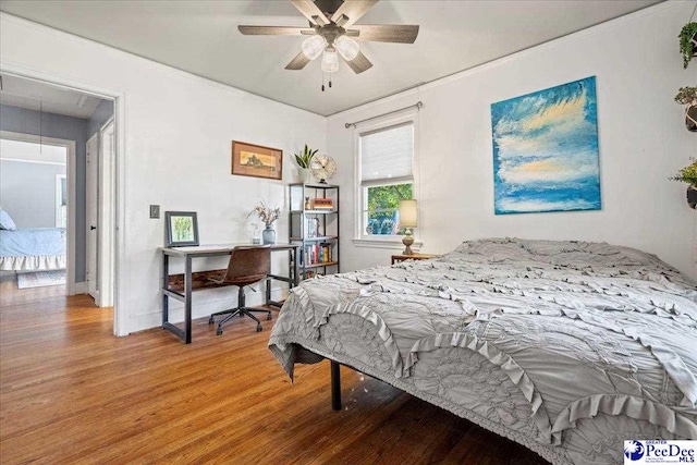 bedroom with a ceiling fan, wood finished floors, attic access, and baseboards