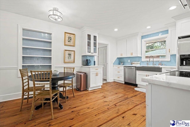 kitchen featuring stainless steel appliances, white cabinetry, decorative backsplash, and light wood finished floors