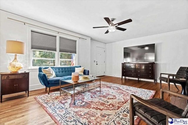 living area featuring baseboards, a ceiling fan, and wood finished floors