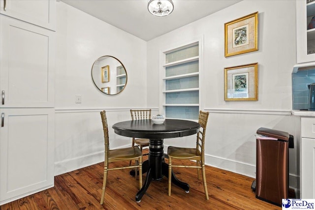 dining area featuring built in shelves, dark wood finished floors, and baseboards