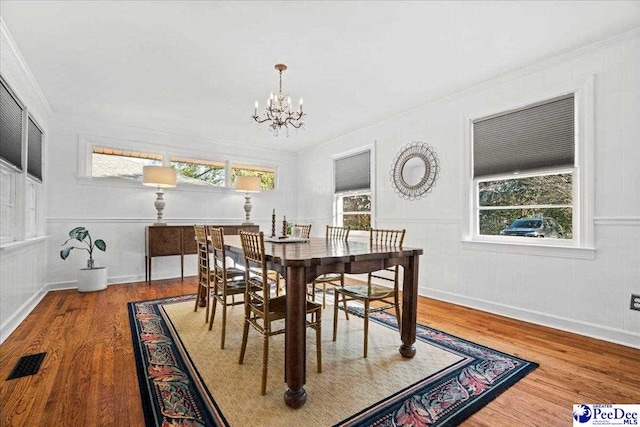 dining room featuring crown molding, wood finished floors, visible vents, and a notable chandelier