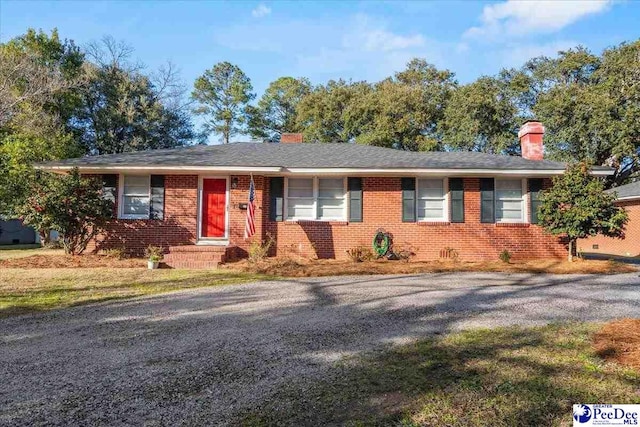 ranch-style home featuring brick siding, driveway, and a chimney