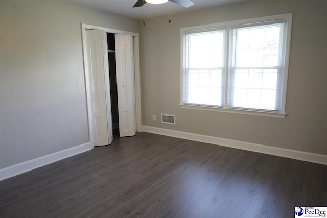 unfurnished bedroom with dark wood-type flooring, a closet, and ceiling fan