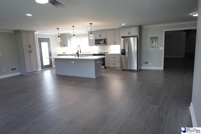 kitchen featuring dark hardwood / wood-style flooring, hanging light fixtures, stainless steel appliances, crown molding, and a center island with sink