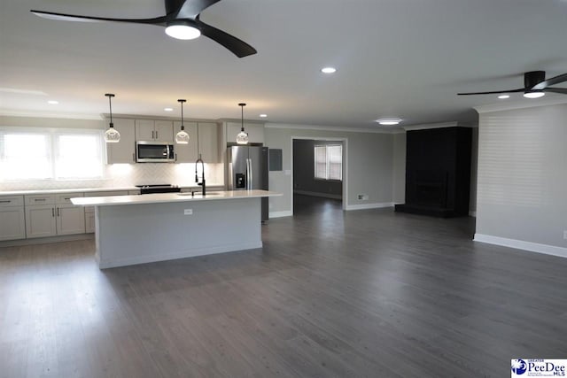 kitchen featuring sink, appliances with stainless steel finishes, hanging light fixtures, a center island, and ornamental molding