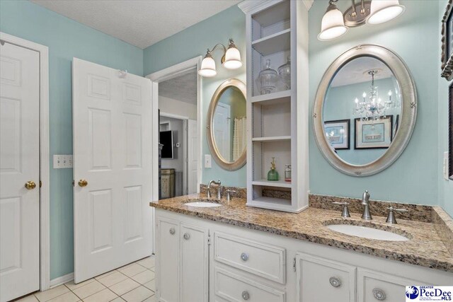 3109 Stillwater Ln, Florence, SC 29501 - bathroom featuring tile patterned floors, double vanity, a chandelier, and a textured ceiling