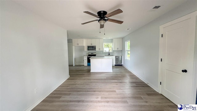 kitchen with white cabinetry, a center island, ceiling fan, light hardwood / wood-style floors, and stainless steel appliances