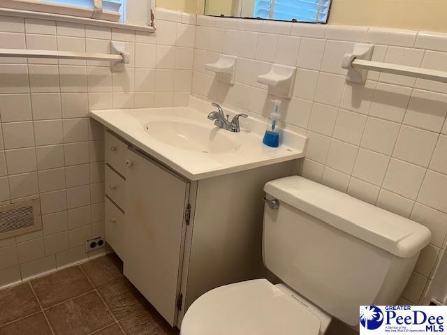 bathroom with tile walls, vanity, tile patterned floors, and toilet