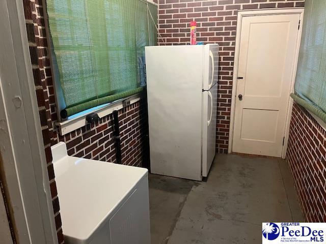 kitchen with white cabinets, brick wall, and white fridge