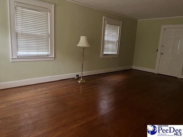 empty room with crown molding and dark hardwood / wood-style flooring