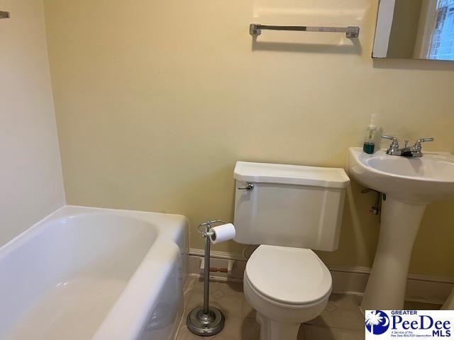 bathroom with sink, a washtub, and toilet