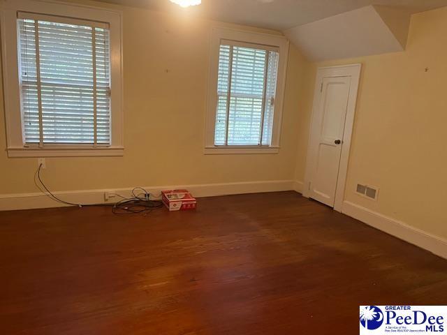 unfurnished room featuring lofted ceiling and dark wood-type flooring