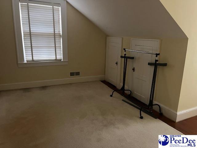 exercise room with vaulted ceiling and carpet flooring