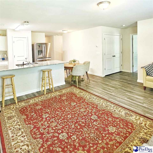 822 Twin Oaks Cir, Lake City, SC 29560 - kitchen featuring stainless steel fridge with ice dispenser, wood finished floors, a breakfast bar area, and a sink